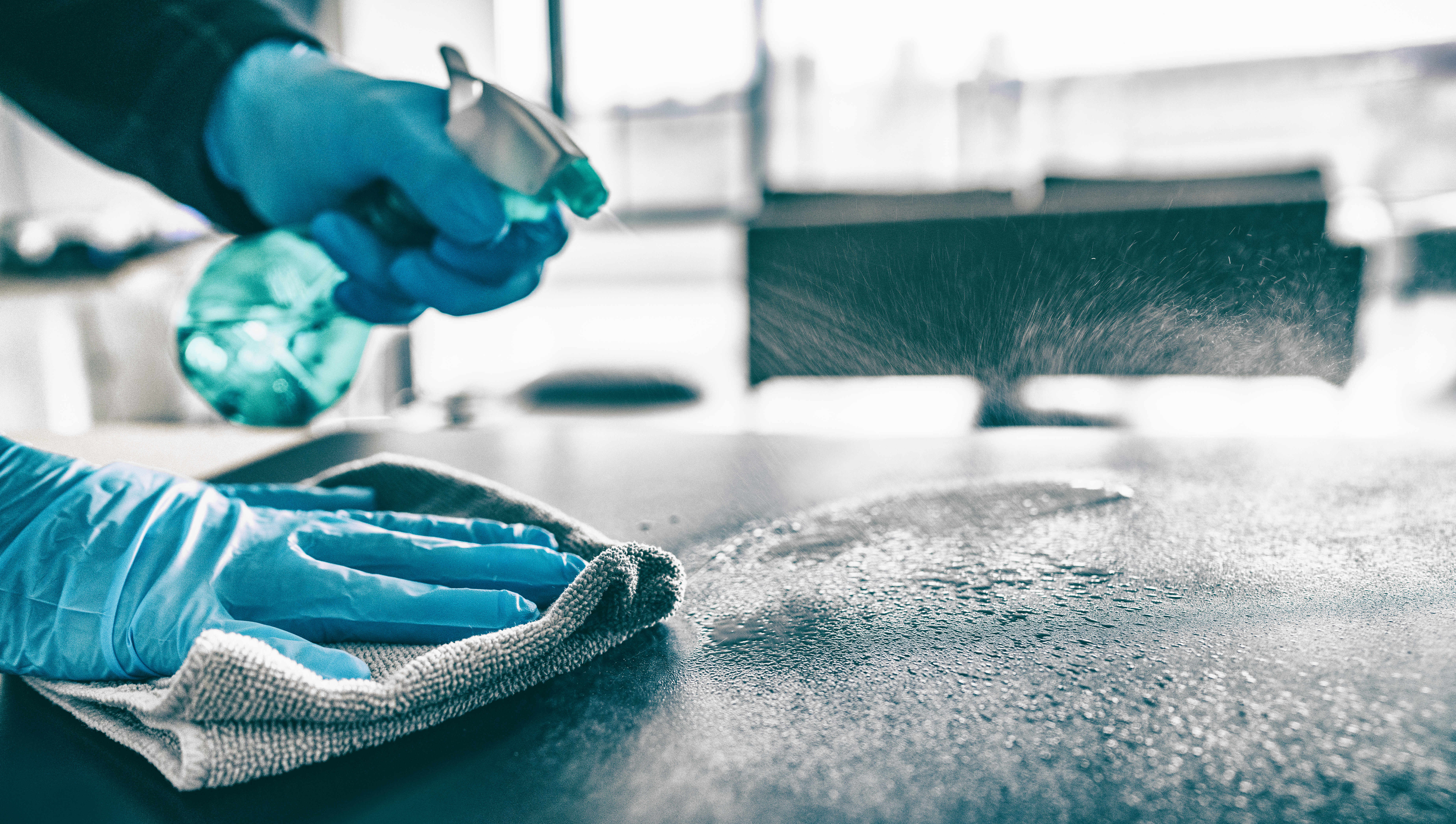 Cleaning home table sanitizing kitchen table surface with disinfectant spray bottle washing surfaces with towel and gloves. COVID-19 prevention sanitizing inside. COSHH Safe Cleaning Services
